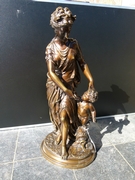 A bronze patinated sculpture of a lady with a putto.